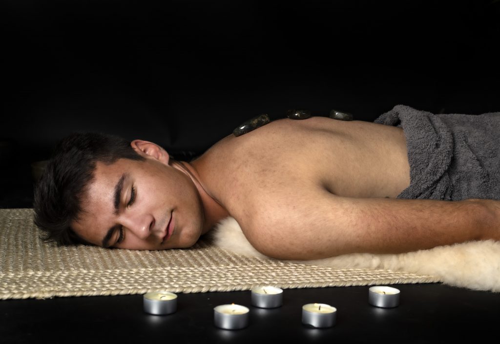 Sensual Male Massage to Enhance Men's Health. Young man laying in a relaxed position ready for his massage.