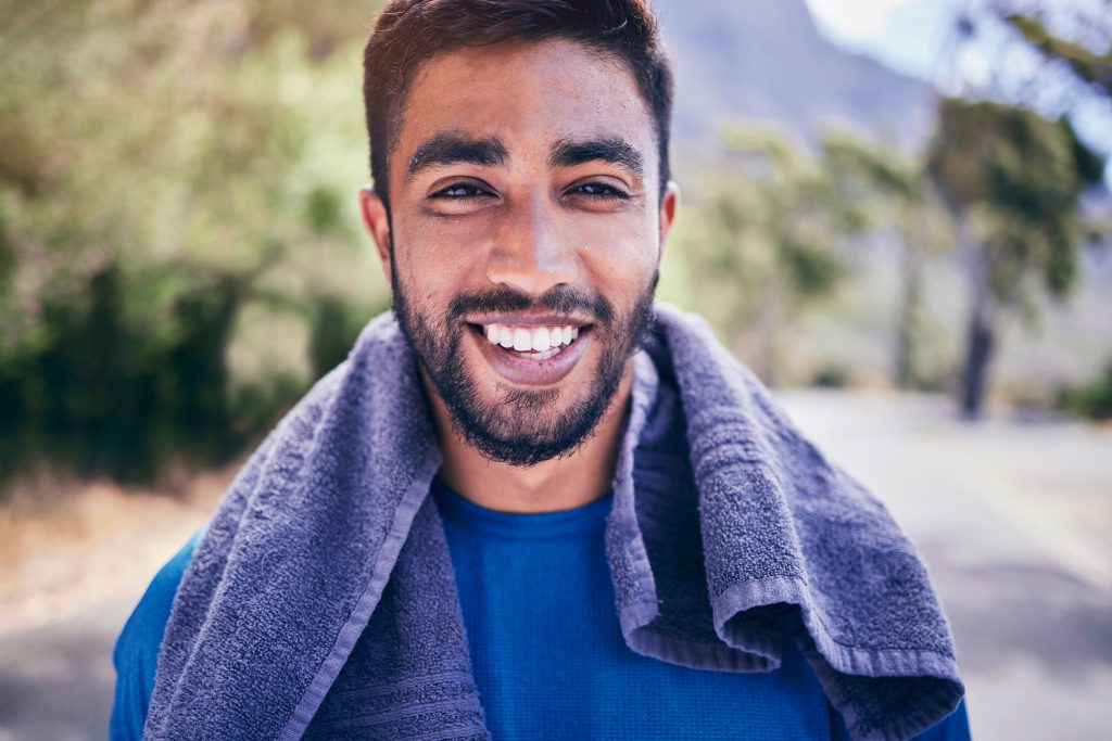 Sensual Male Massage to Enhance Men's Health. Portrait, fitness and smile of man in park with towel for break from exercise, workout and running.