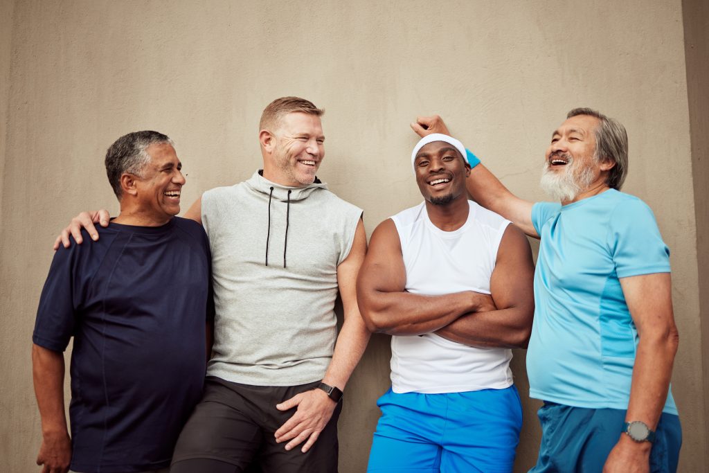 Happy men, exercise group and laughing in city on wall background outdoors. The male G-spot: getting a prostate massage.