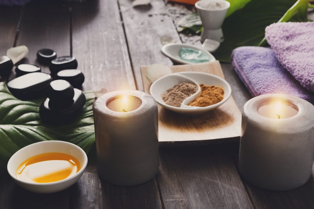 zen spa set-up with soft stones, candles, oil, and towels in a soft light-setting for tantric gay massage.